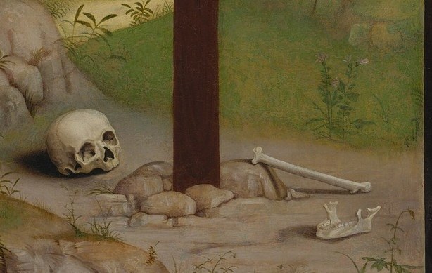 The skull of Adam , a medieval theological convention placing Christ's redemption directly above humanity's first death; a close-up delivers the altarpiece's entire argument in a single image.