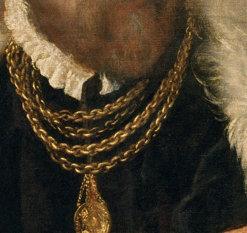 He wears a heavy gold necklace, a clear sign of his wealth.