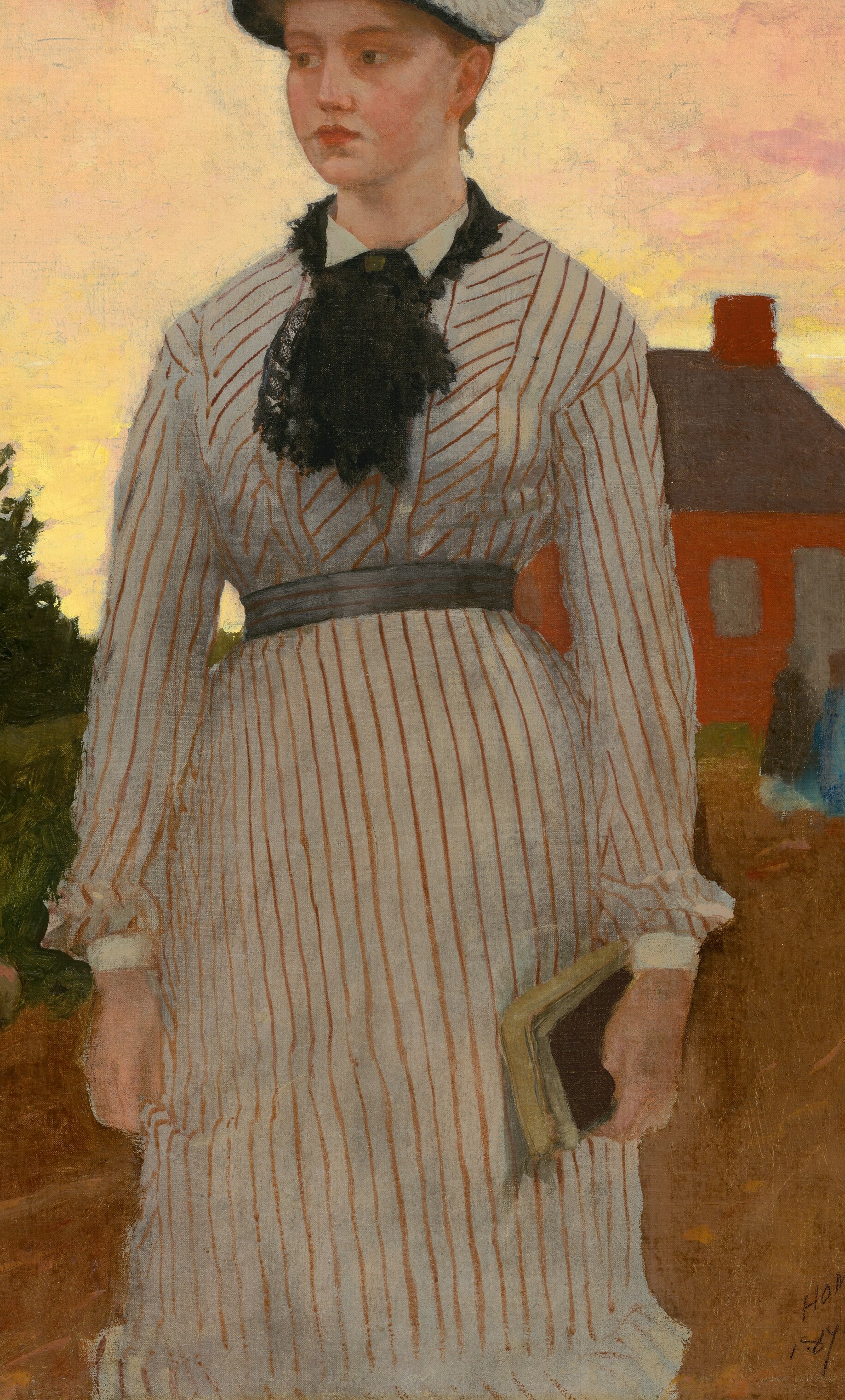 A young woman stands before the bright red schoolhouse.