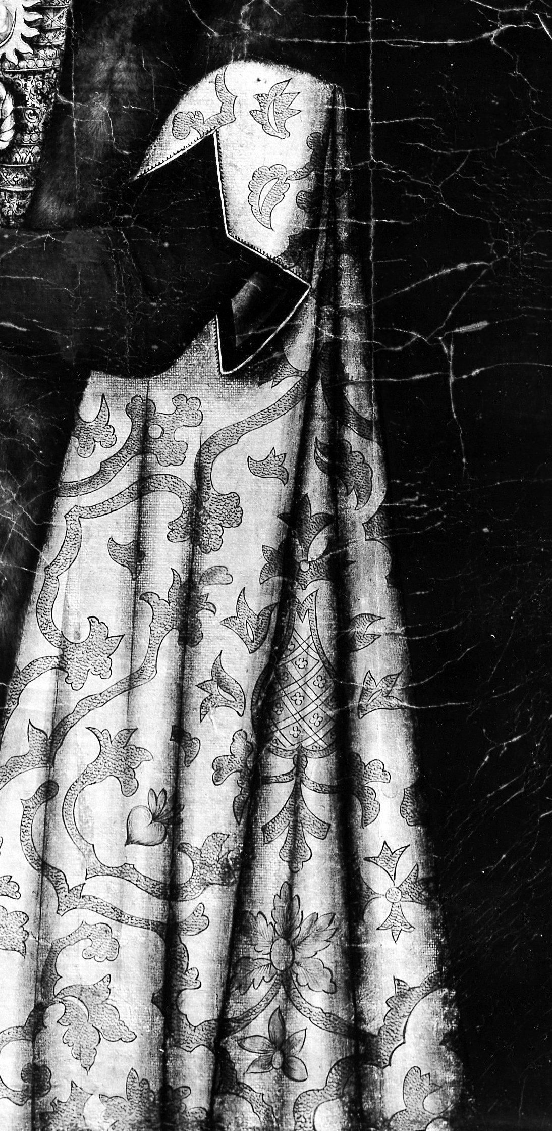 The large, ornately patterned mantle draped over her shoulder is a striking visual element, showcasing intricate design.