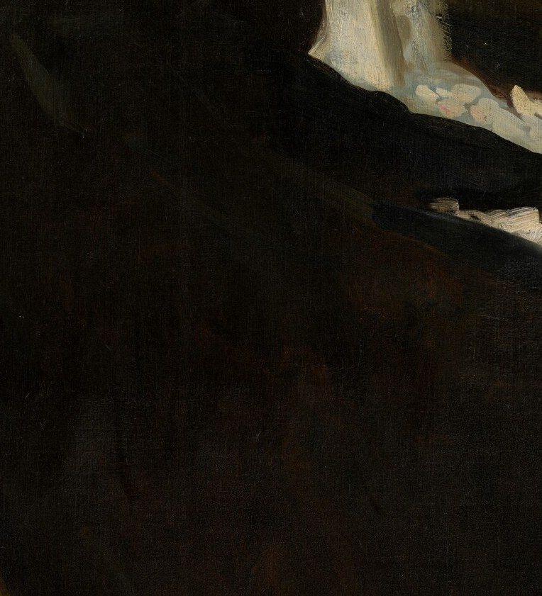 Her hands are still. A folded fan. A woman accustomed to being watched.