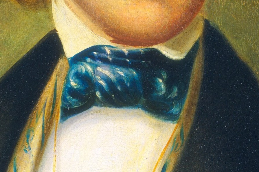 His formal attire, a black jacket and blue bow tie, hints at his status.