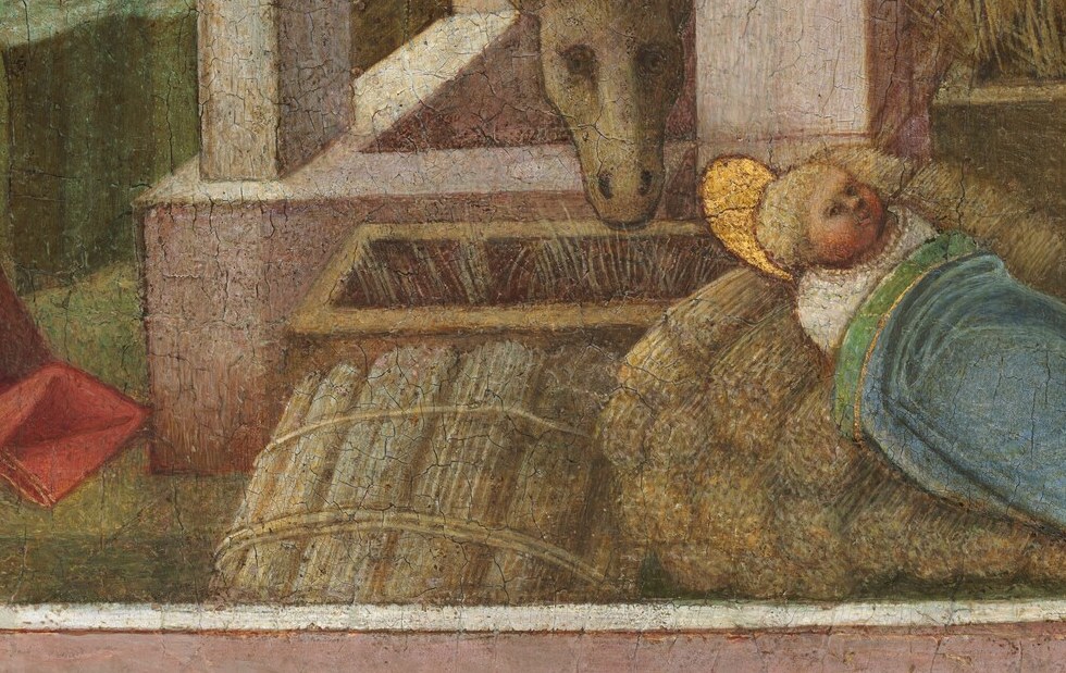The infant lies on bare earth, not a manger.