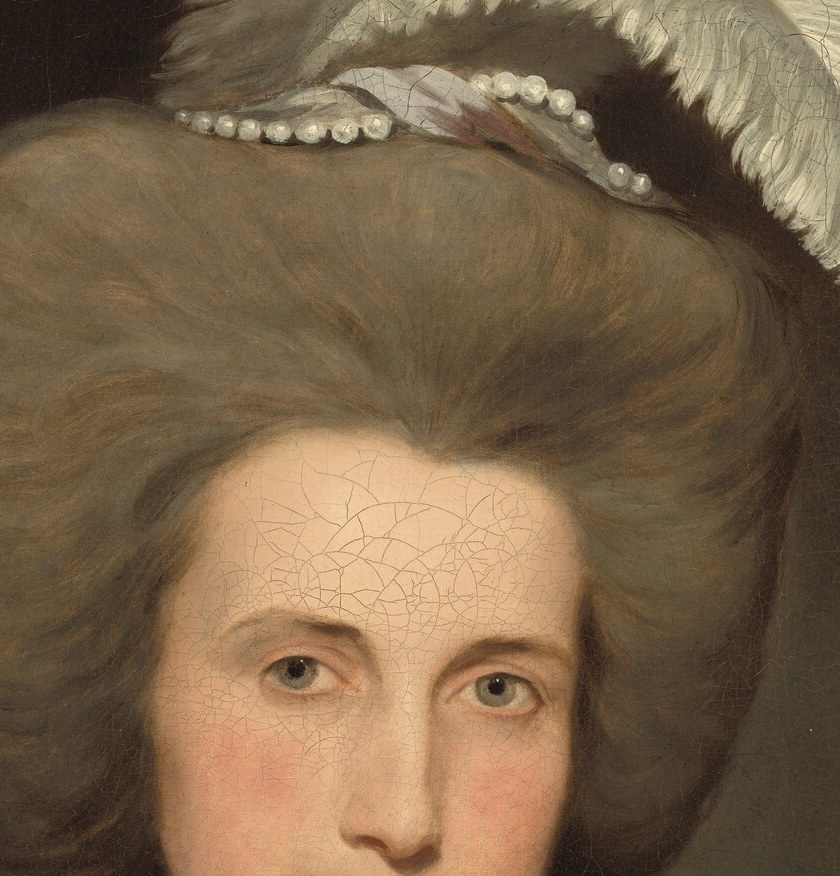 She wears pearls and an elaborate feathered hat.