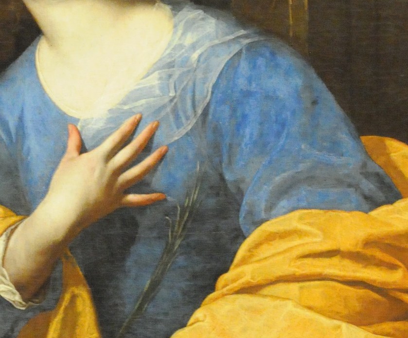 Look closely for the symbol of her martyrdom.