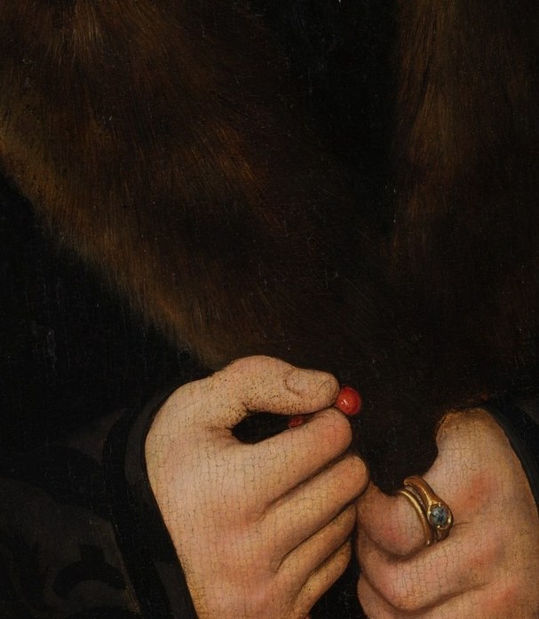 They hold a rosary. Red beads, the only color in the frame.