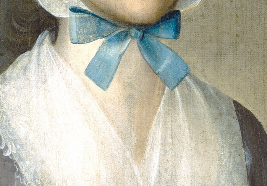 She wears a delicate lace collar and blue ribbon.