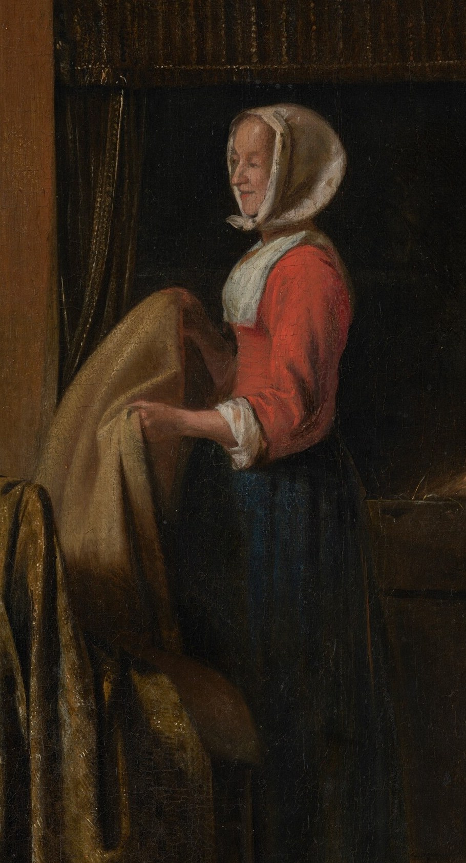 A woman carefully folds a patterned cloth.