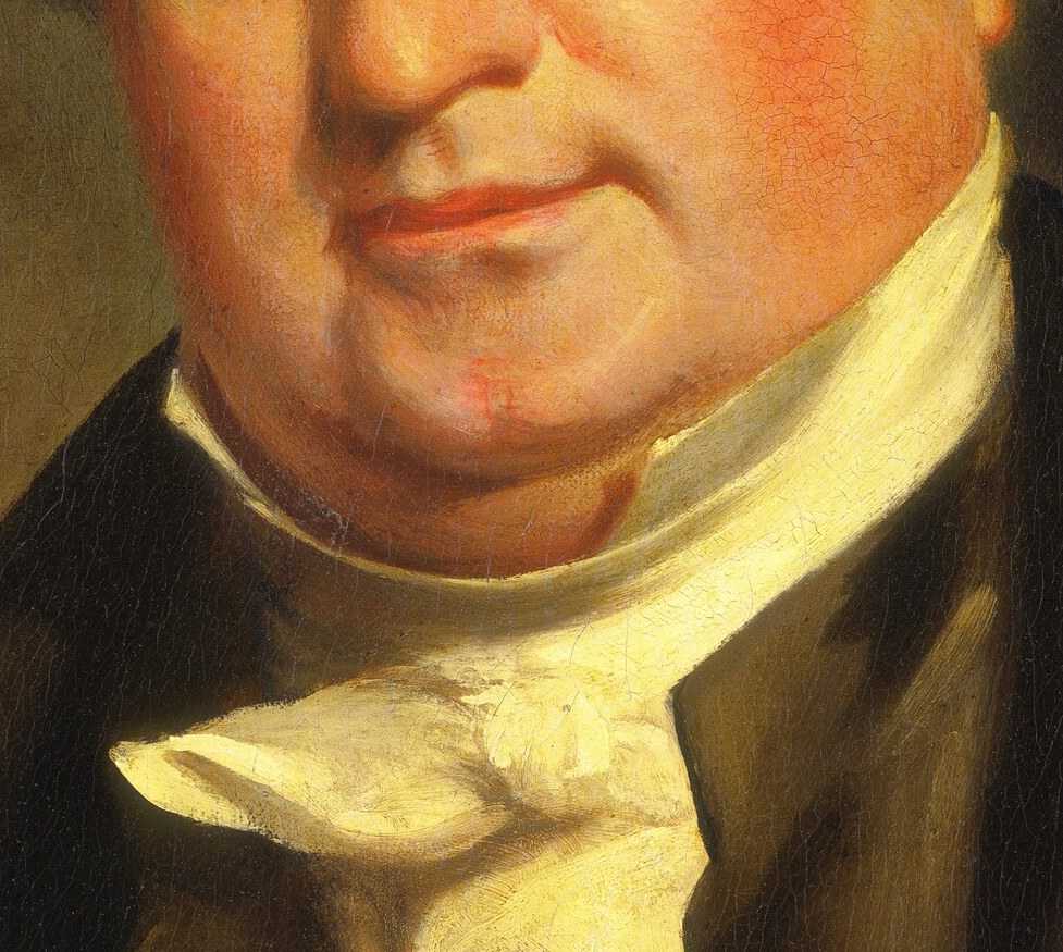The crisp white fabric contrasts sharply with his dark attire, drawing attention to his neck and face.