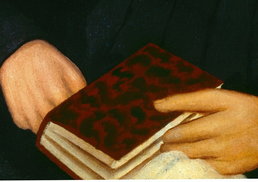 Her hands, gently folded, hold a book.