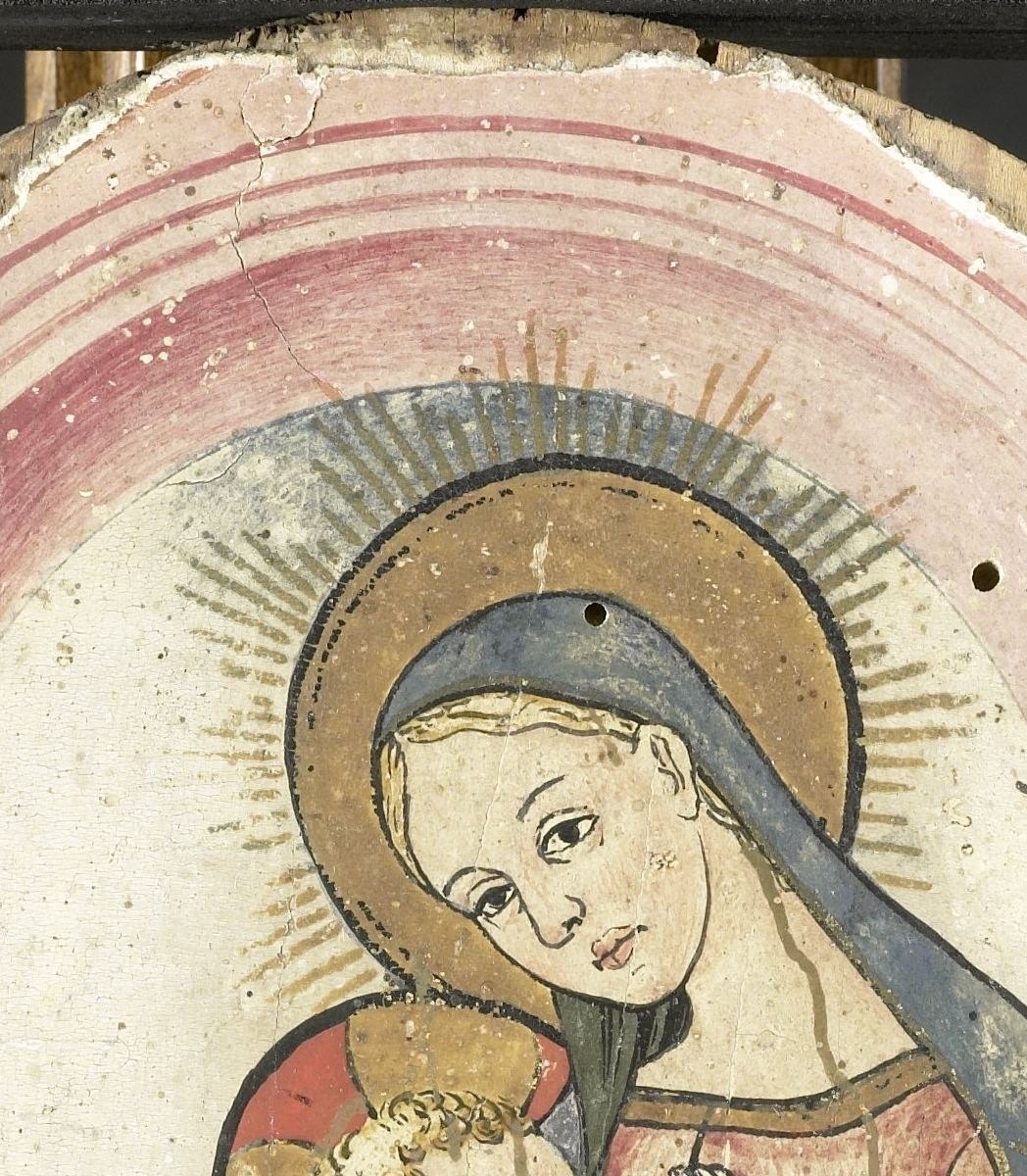 The serene, slightly downward gaze and halo define her devotional role; her expression carries the painting's emotional center.