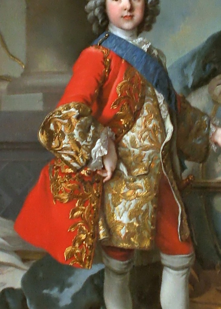 The crimson coat with gold thread is the visual weight of the monarchy itself.