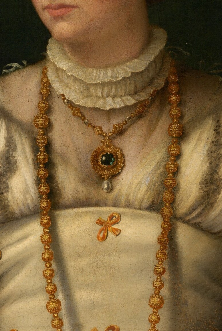 Look closely at the detailed gold necklace and pendant.
