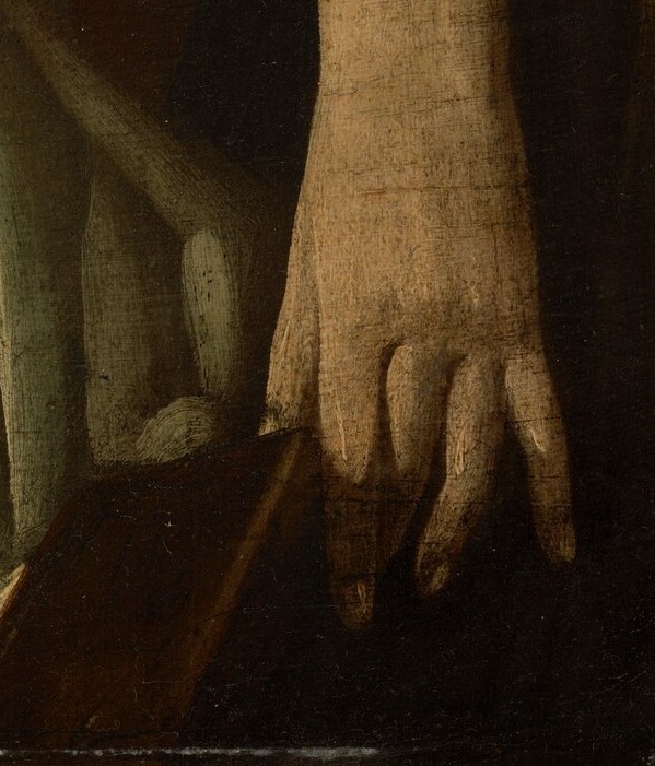 Her right hand rests on a dark surface, its fingers slightly splayed, suggesting a moment of stillness or perhaps weariness.