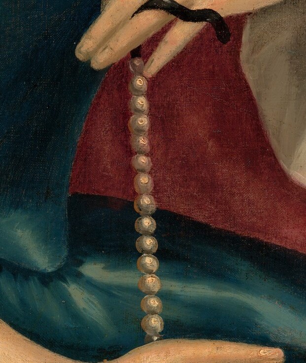 She wears a blue satin dress and a delicate pearl necklace.