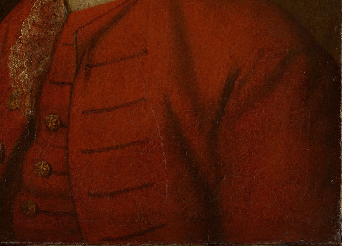 His red coat and gold buttons signal wealth and status.