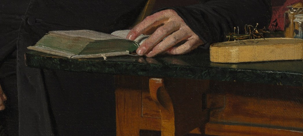 Look closely at the objects on his desk.