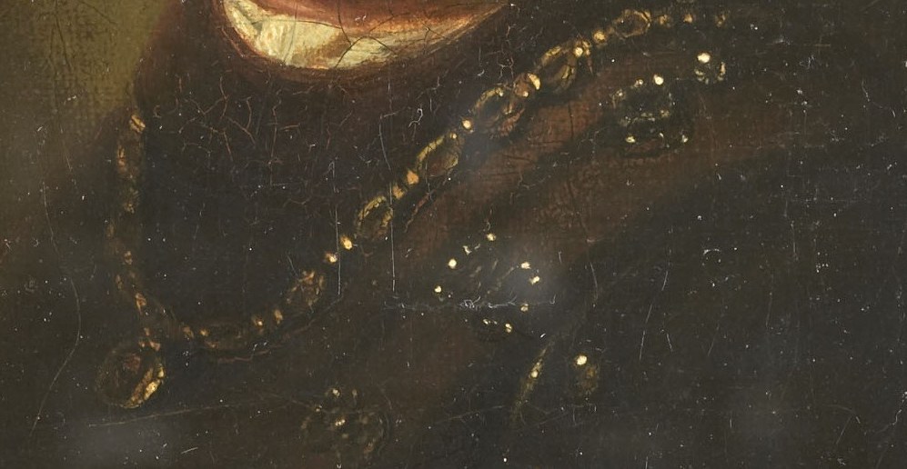 Around his neck: a heavy, ornate gold chain.