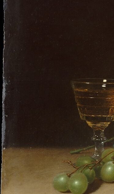 A glass of pale wine catches the light through its bowl.