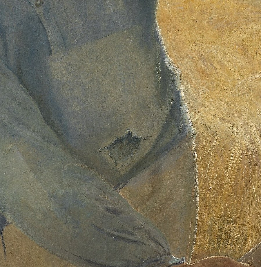 A shadow falls across his tired shirt.