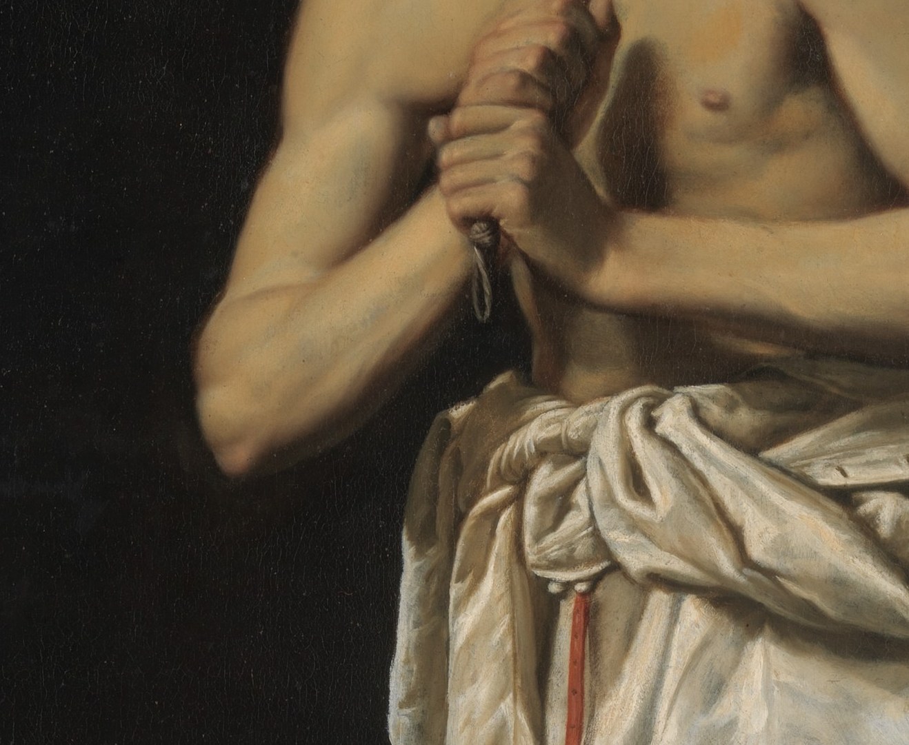 He kneels in shadow, about to bring the whip down.