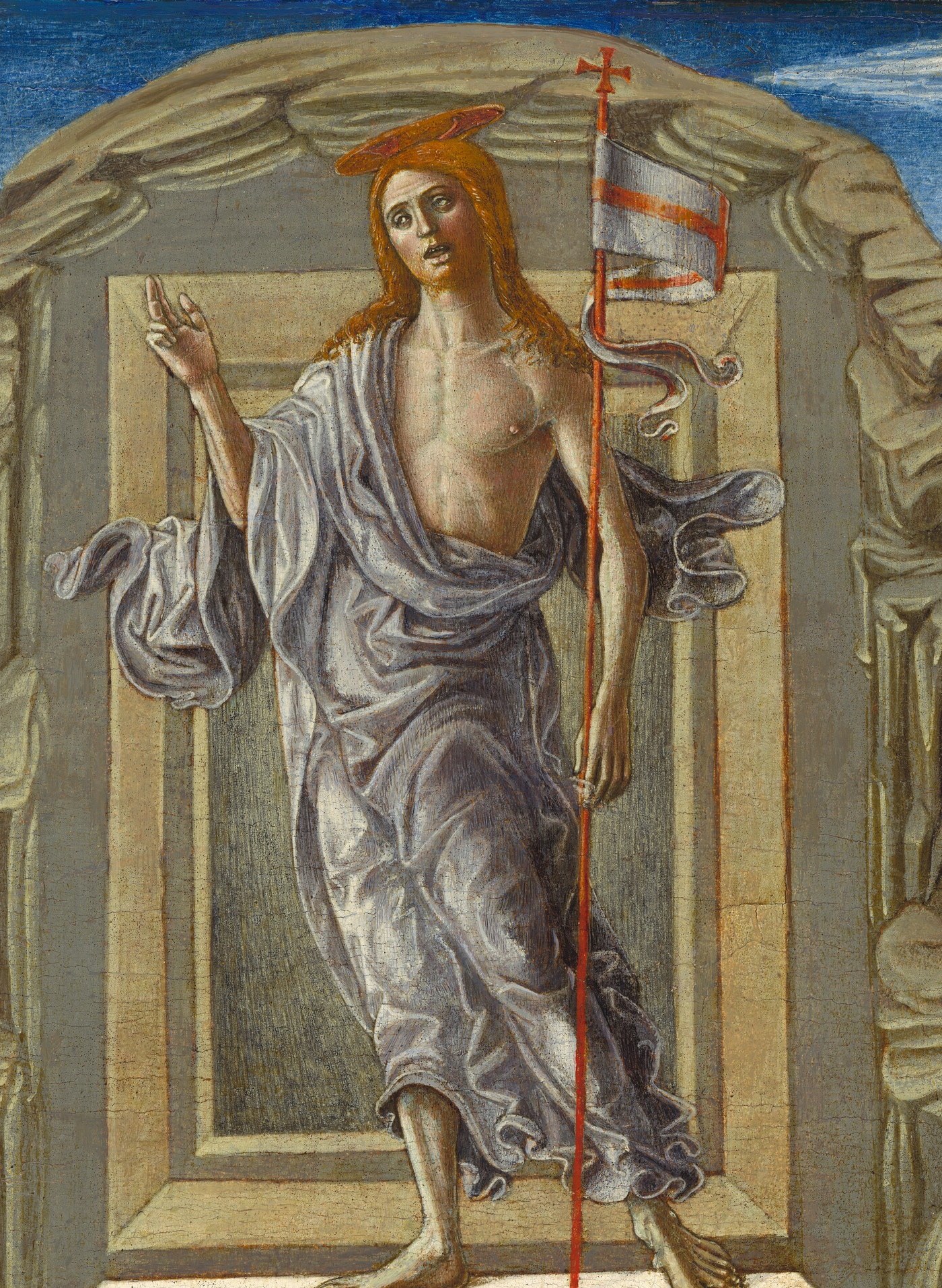 The resurrected Christ dominates the vertical axis , bare-chested, draped in blue-white from the waist down, one hand raised in benediction and the other gripping the banner staff; his calm posture against a chaos of fallen soldiers is the painting's central dramatic argument.