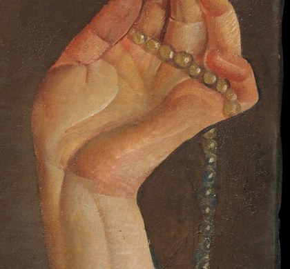 She also holds a string of rosary beads.