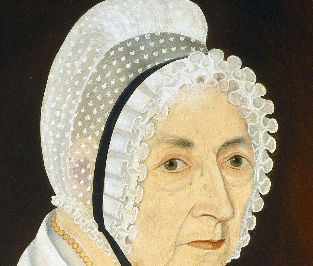 She wears a delicate, lace-trimmed bonnet.