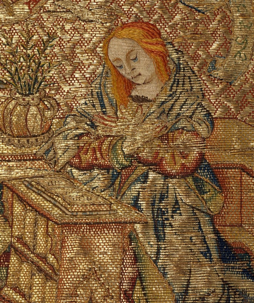 Every fold of her blue robe is built from thousands of silent stitches.