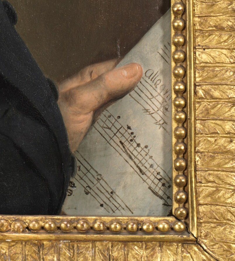 He holds musical notation, but no instrument.
