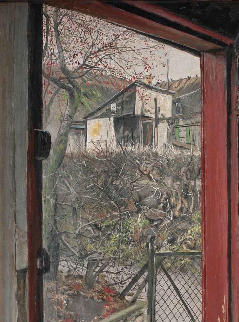He stands looking out at bare trees and a gray sky.